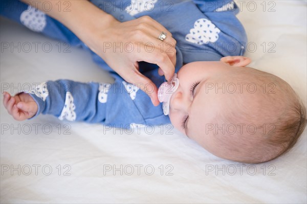 Caucasian mother giving baby daughter pacifier