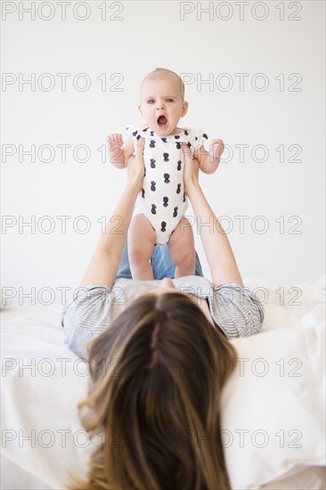Caucasian mother holding baby daughter on bed