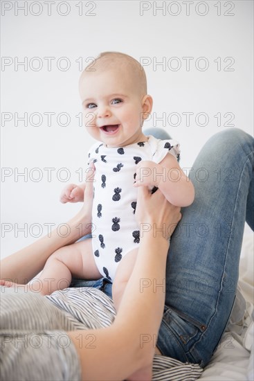 Caucasian mother holding baby daughter on bed