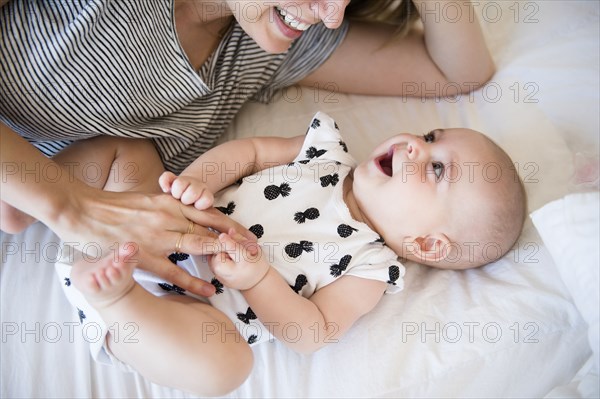 Caucasian mother and baby daughter laying on bed