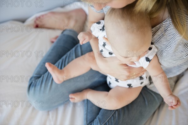 Caucasian mother holding baby daughter on bed