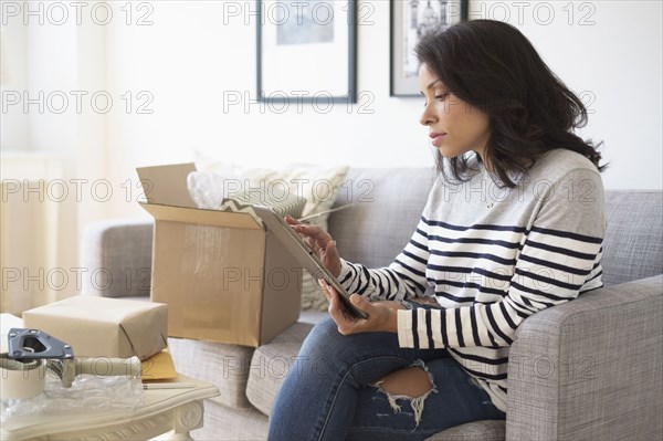 Mixed race business owner using digital tablet on sofa