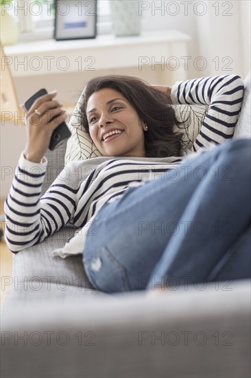 Mixed race woman using cell phone on sofa