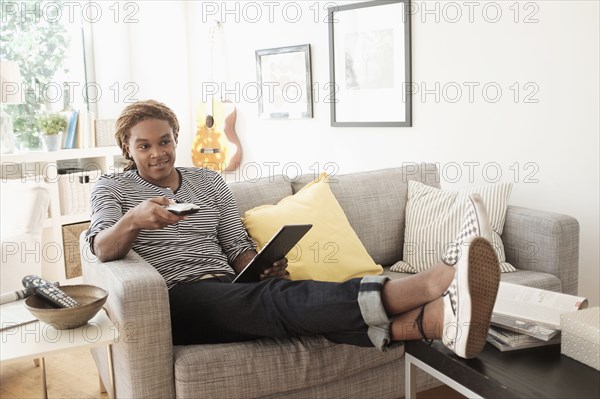 Mixed race man watching television on sofa