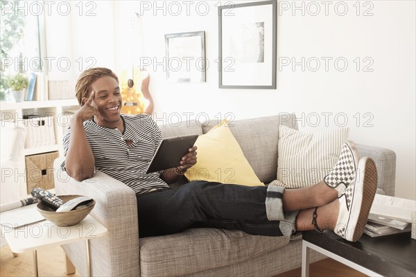 Mixed race man using digital tablet on sofa
