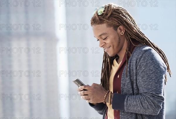Mixed race man using cell phone outdoors