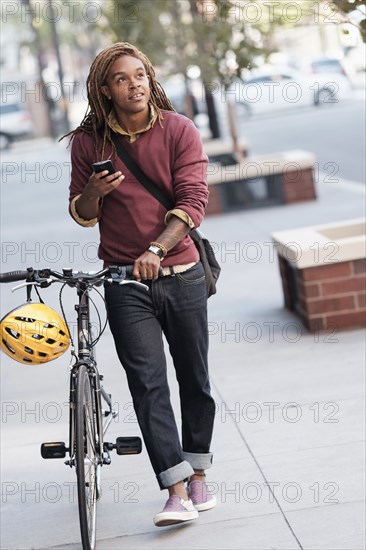 Mixed race man pushing bicycle outdoors