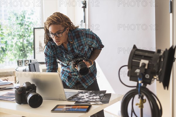 Mixed race photographer using laptop in studio