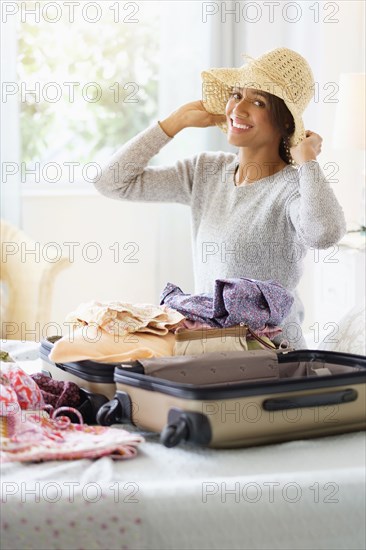 Mixed race woman packing suitcase in bed