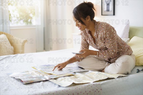 Mixed race woman reading map in bed