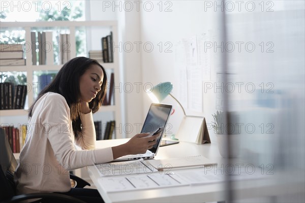 Mixed race businesswoman using cell phone