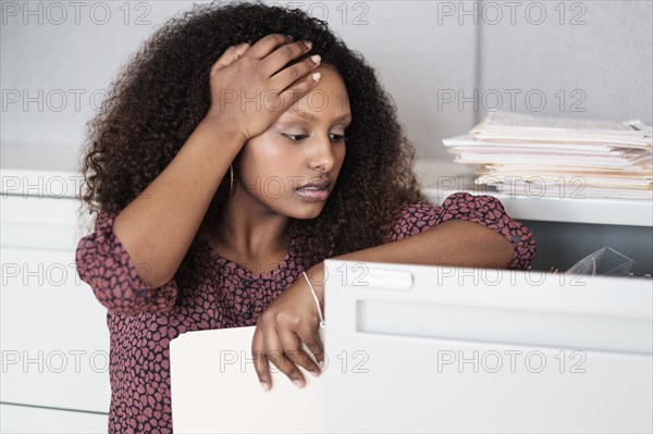 Black businesswoman searching in filing cabinet