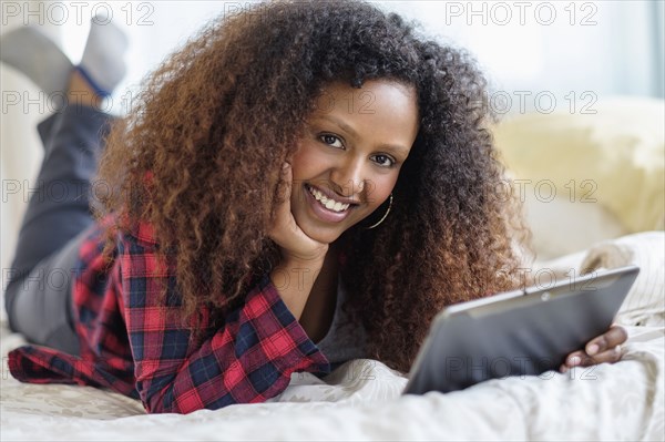 Black woman using digital tablet on bed