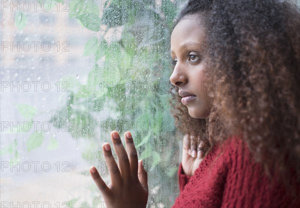 Black woman looking out rainy window