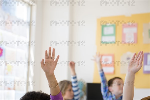 Students raising hands in classroom