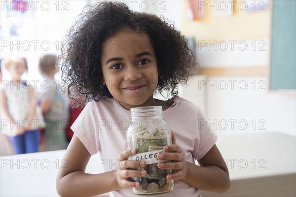 Student holding savings jar in classroom