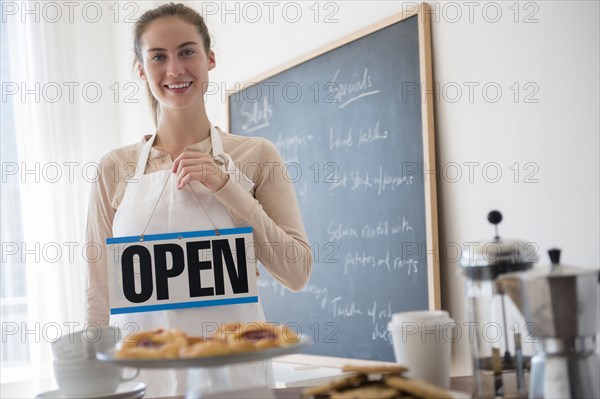 Native American woman holding open sign in cafe