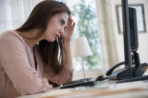 Frustrated Native American businesswoman working at computer