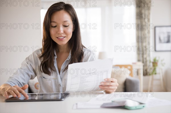 Mixed race woman paying bills on digital tablet