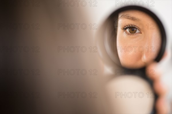 Mixed race woman admiring herself in compact mirror