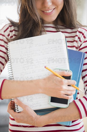 Mixed race student holding homework and cell phone