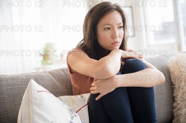 Sad mixed race woman sitting on sofa