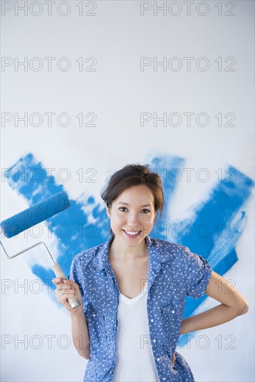 Mixed race woman painting wall