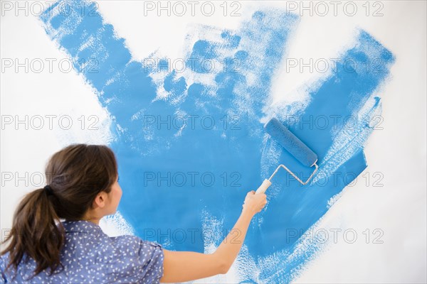 Mixed race woman painting wall