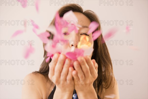 Mixed race woman blowing confetti