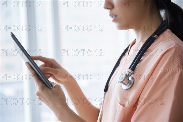 Mixed race nurse using digital tablet