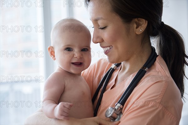 Nurse holding baby girl in hospital