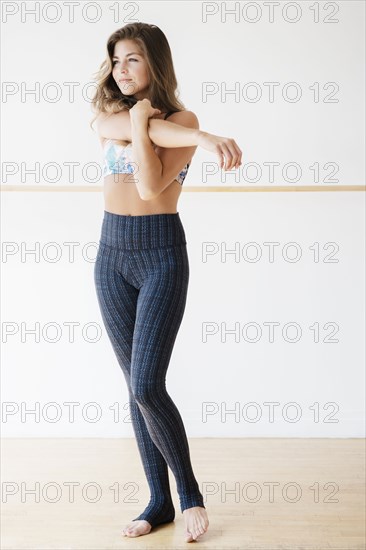 Mixed race dancer stretching in studio