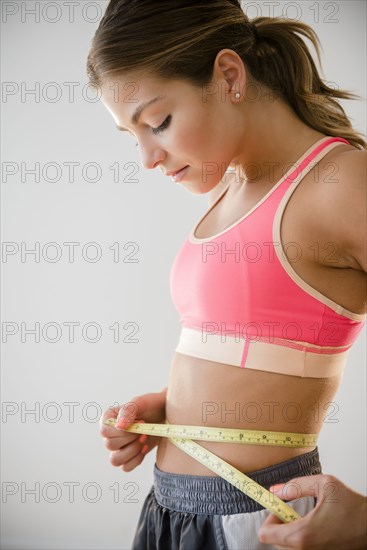 Mixed race woman measuring her waist