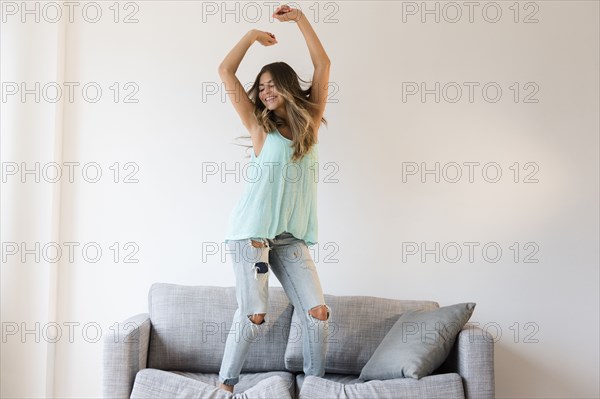 Mixed race woman jumping on sofa