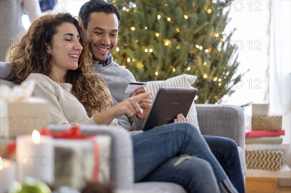 Couple shopping with digital tablet on sofa
