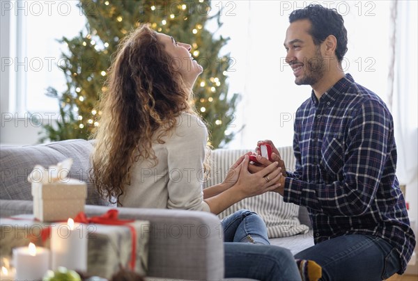 Man proposing to girlfriend on sofa