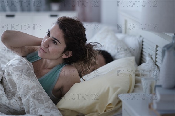 Woman rubbing her neck in bed