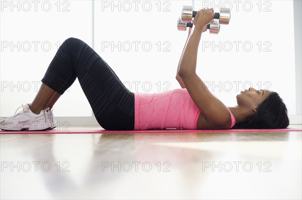 Mixed race woman lifting weights