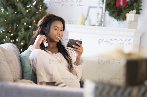 Mixed race woman using cell phone on sofa