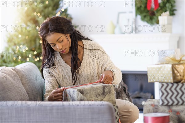 Mixed race woman wrapping Christmas gifts