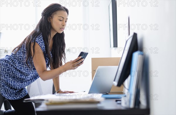 Mixed race businesswoman using cell phone