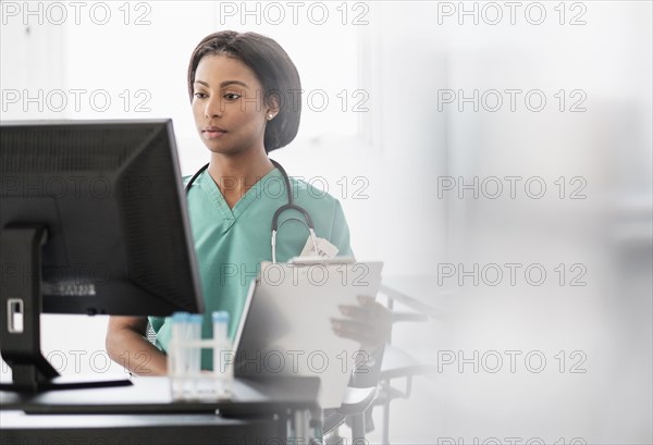 Mixed race nurse smiling at computer