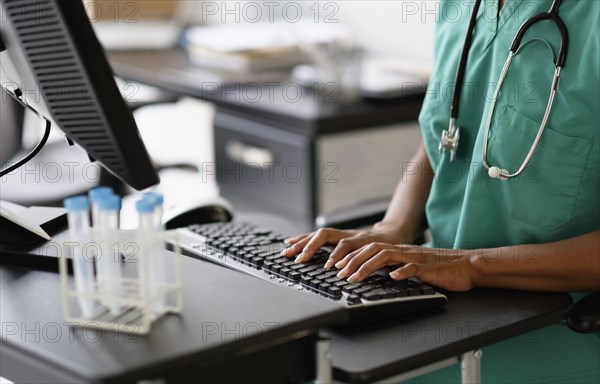 Mixed race nurse working at computer