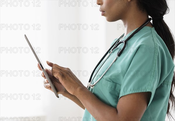 Mixed race nurse using digital tablet