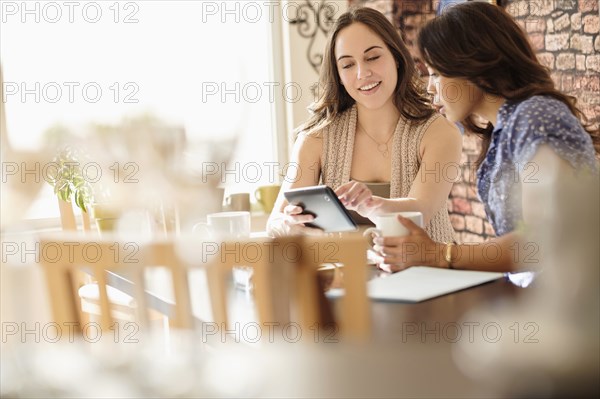 Women using digital tablet in coffee shop