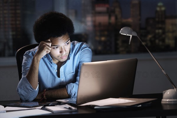 Mixed race businessman working late in office