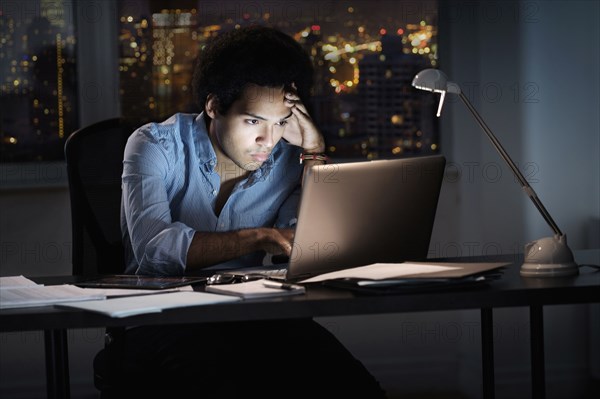 Mixed race businessman working late in office