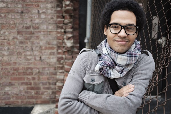 Mixed race man leaning on chain link fence