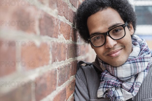 Mixed race man leaning on brick wall