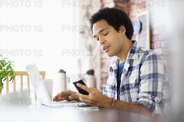 Mixed race man multitasking in coffee shop